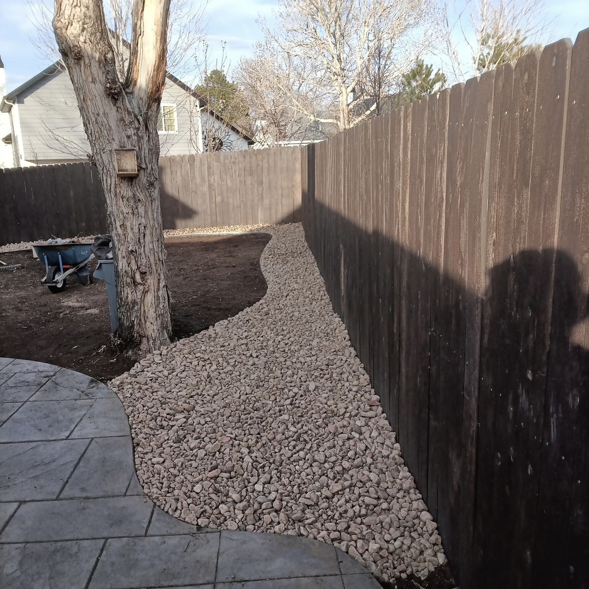 Decorative river rock border along a backyard fence